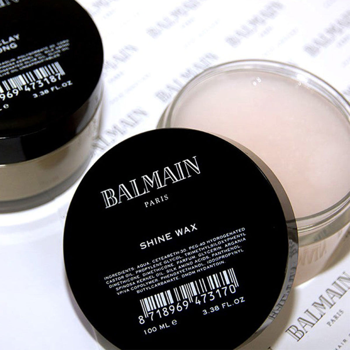 Balmain shine wax container with black lid and white body on a light background