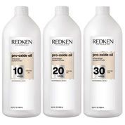 Three large white bottles of Redken Pro-Oxide Oil in 10, 20, and 30 volumes, arranged side by side on a white background.