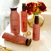 PUREology hair care products on a white surface with flowers in the background