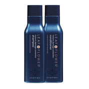 Two blue bottles of LEAF & FLOWER shampoo and conditioner on a white background