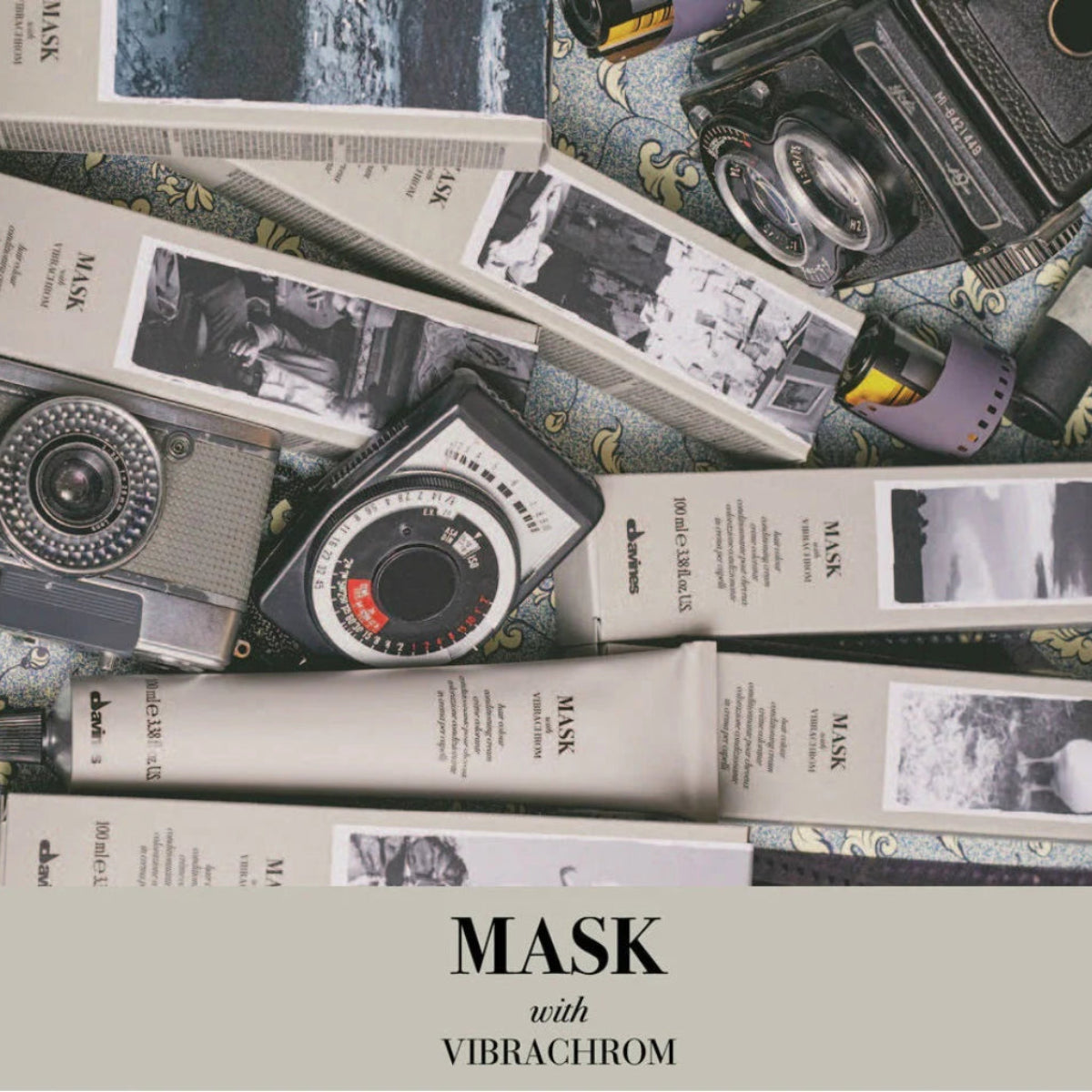 Tubes of 'MASK' with 'Vibrachrom' on a surface with vintage camera and photo album items.