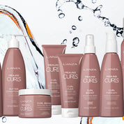 LANZA Healing Curls hair care set featuring multiple bottles and jars in a dusty rose color, arranged against a white background with water splashes and orange slices. A black 'NEW!' badge is in the top right corner.
