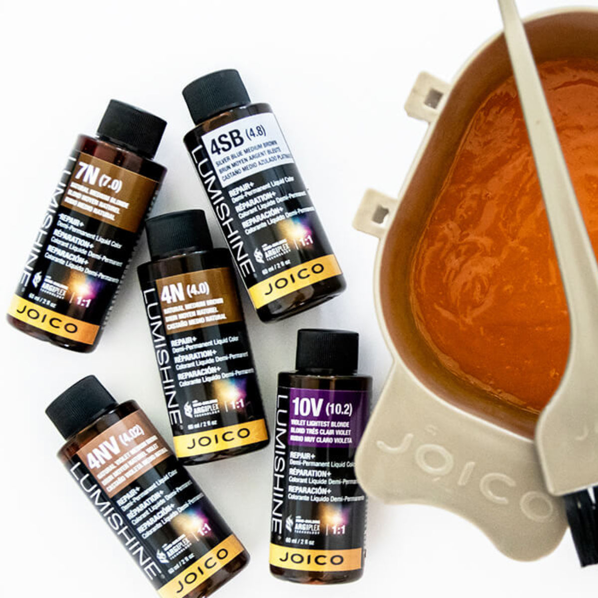 Joico hair color products with a color mixing bowl and brush on a white background