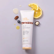 Tube of 'milk shake' curl passion product with lemon slices and berries on a light purple background