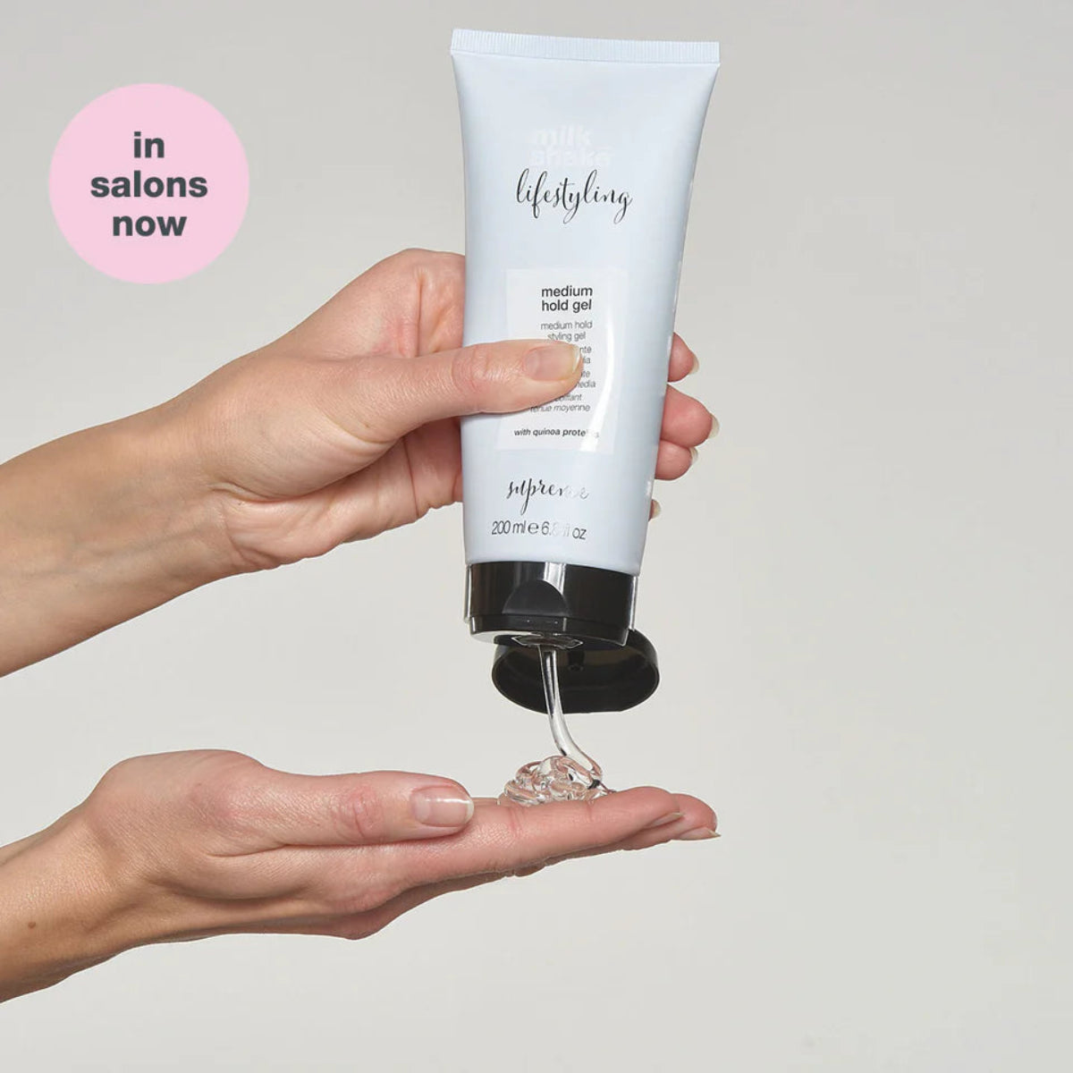 Hand holding a tube of 'lifestyling' medium hold gel with a small amount on an open palm against a plain background.