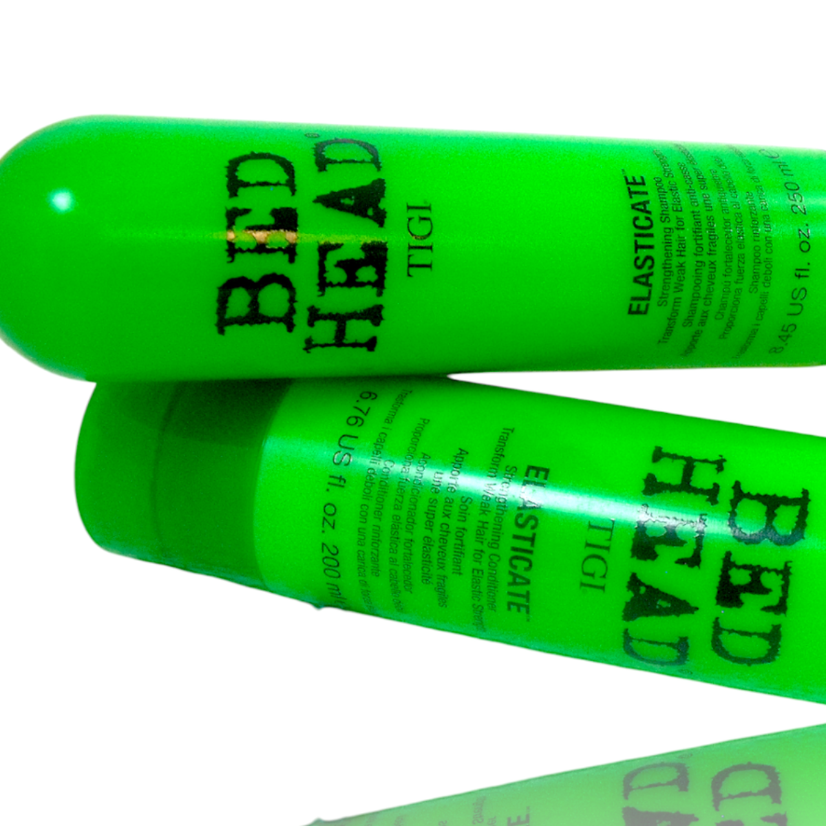 Two bright neon green bottles of Tigi Bed Head Elasticitate hair elastic gel, arranged diagonally on a white background with a reflection below.